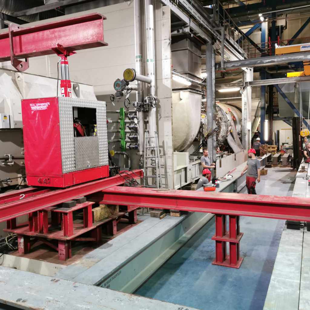 Anlagenteil wird in einer Industriehalle auf roten Stahlträgern ausgerichtet