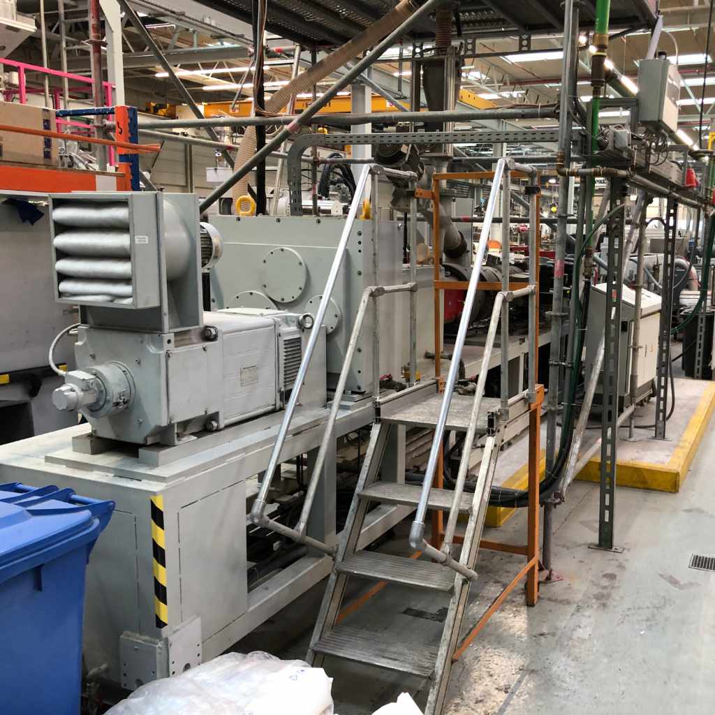 Industrieanlage in einer Produktionshalle mit Antrieb, Getriebe und Aufstiegstreppe