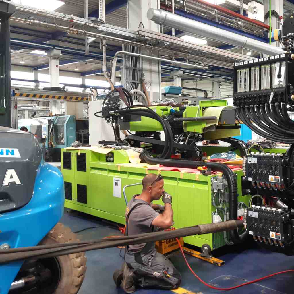 Teleskoplader hebt einen Behälter vor einer Industriehalle von Markewitsch Engineering